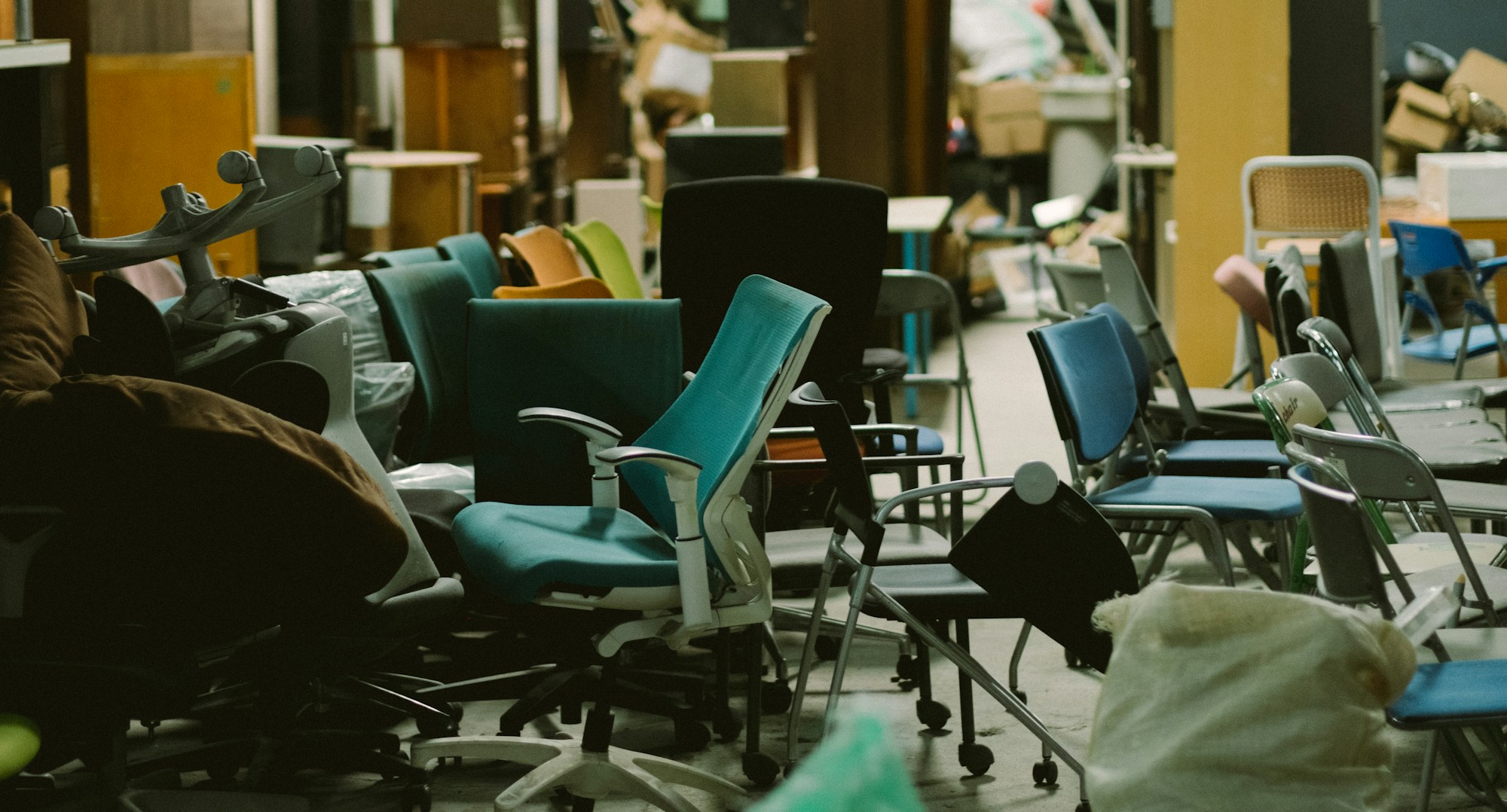 A warehouse packed with surplus office chairs, cabinets and boxes